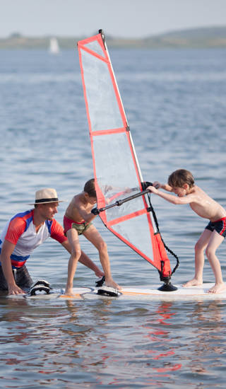Kinderen op surfplank trainen met coach