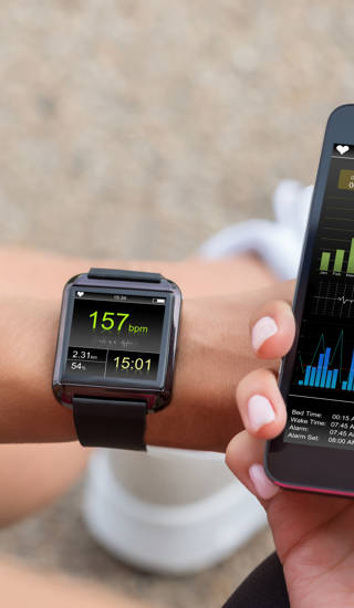Female Runner Looking At Her Mobile And Smart Watch Heart Rate Monitor