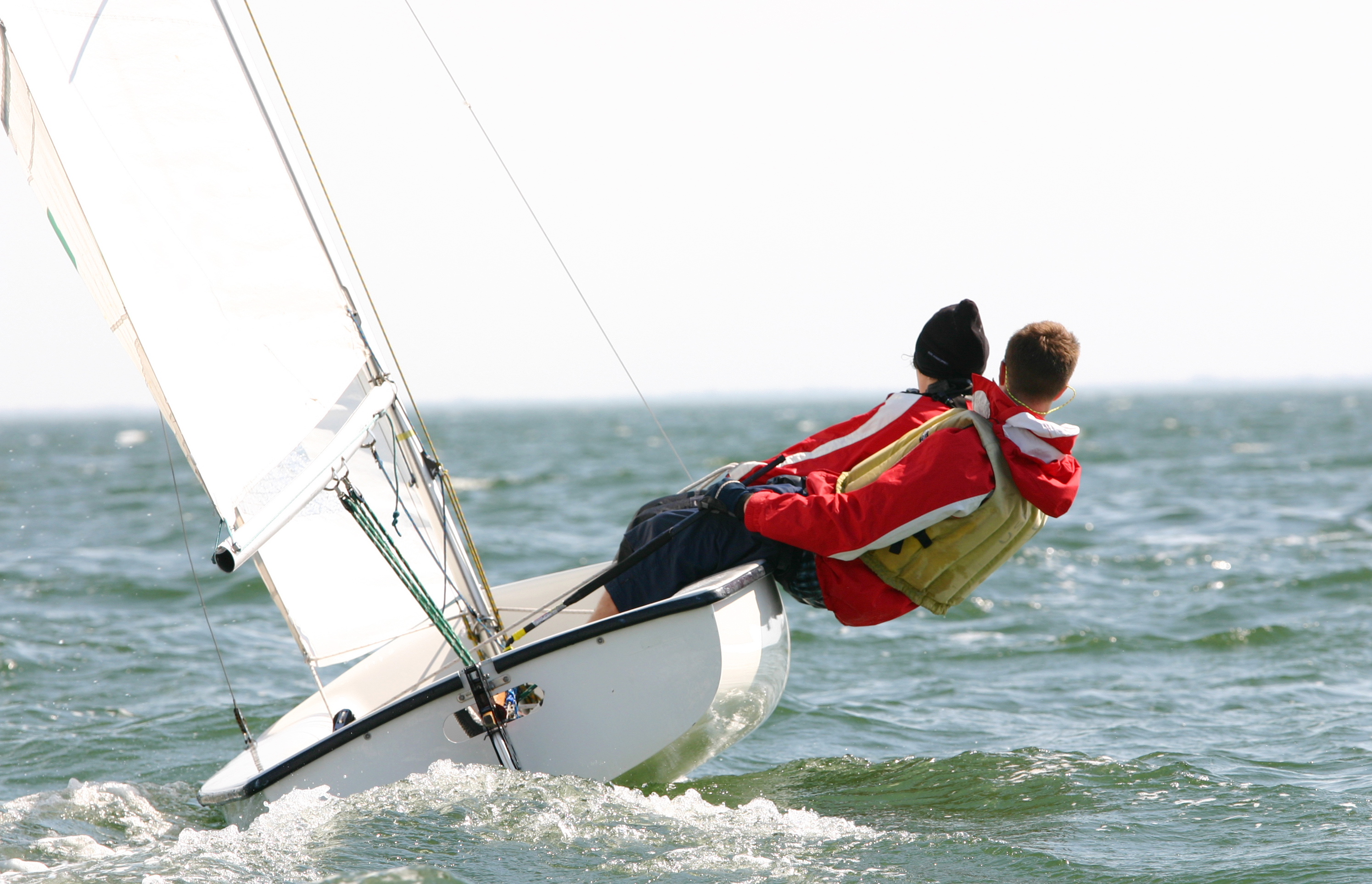 Twee jongeren hangen buiten boord op zeilboot