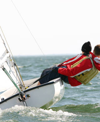 Twee jongeren hangen buiten boord op zeilboot