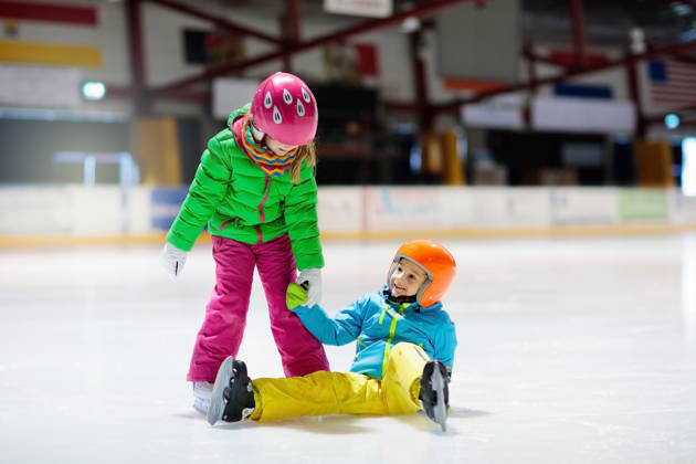 Twee kinderen schaatsen indoor, ene is gevallen