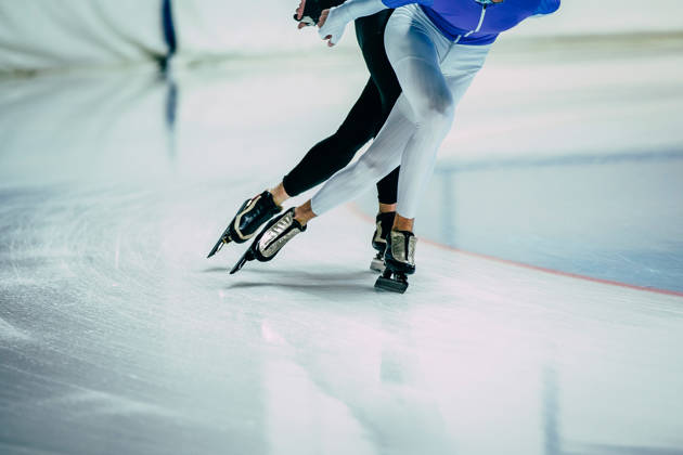 Benen van twee schaatsers die aan het schaatsen zijn indoor 