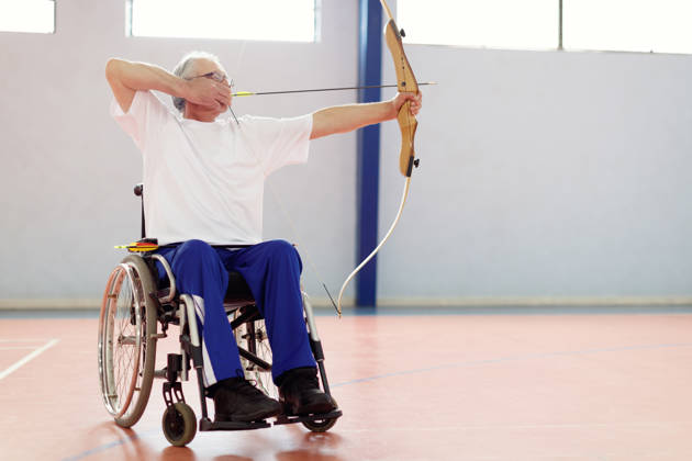 Oudere man in rolstoel met pijl en boog