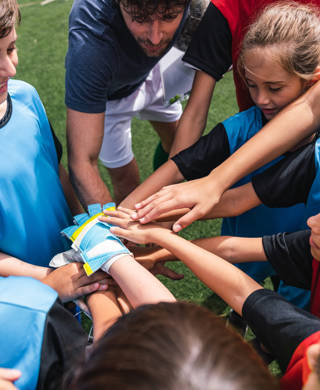 Female and male kids soccer players together with hands in circle before a match. High angle view