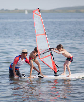 Kinderen op surfplank trainen met coach