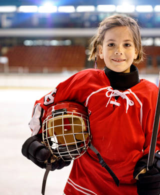 Meisje in ijshockeyuitrusting kijkt in camera 