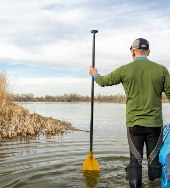 early spring stand up paddling, senior male with his paddleboard on lake in Colorado