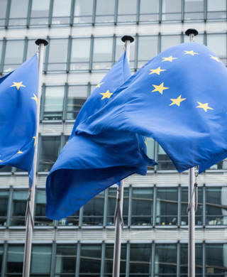 Drie Europese vlaggen wapperen voor het gebouw van de Europese Unie in Brussel