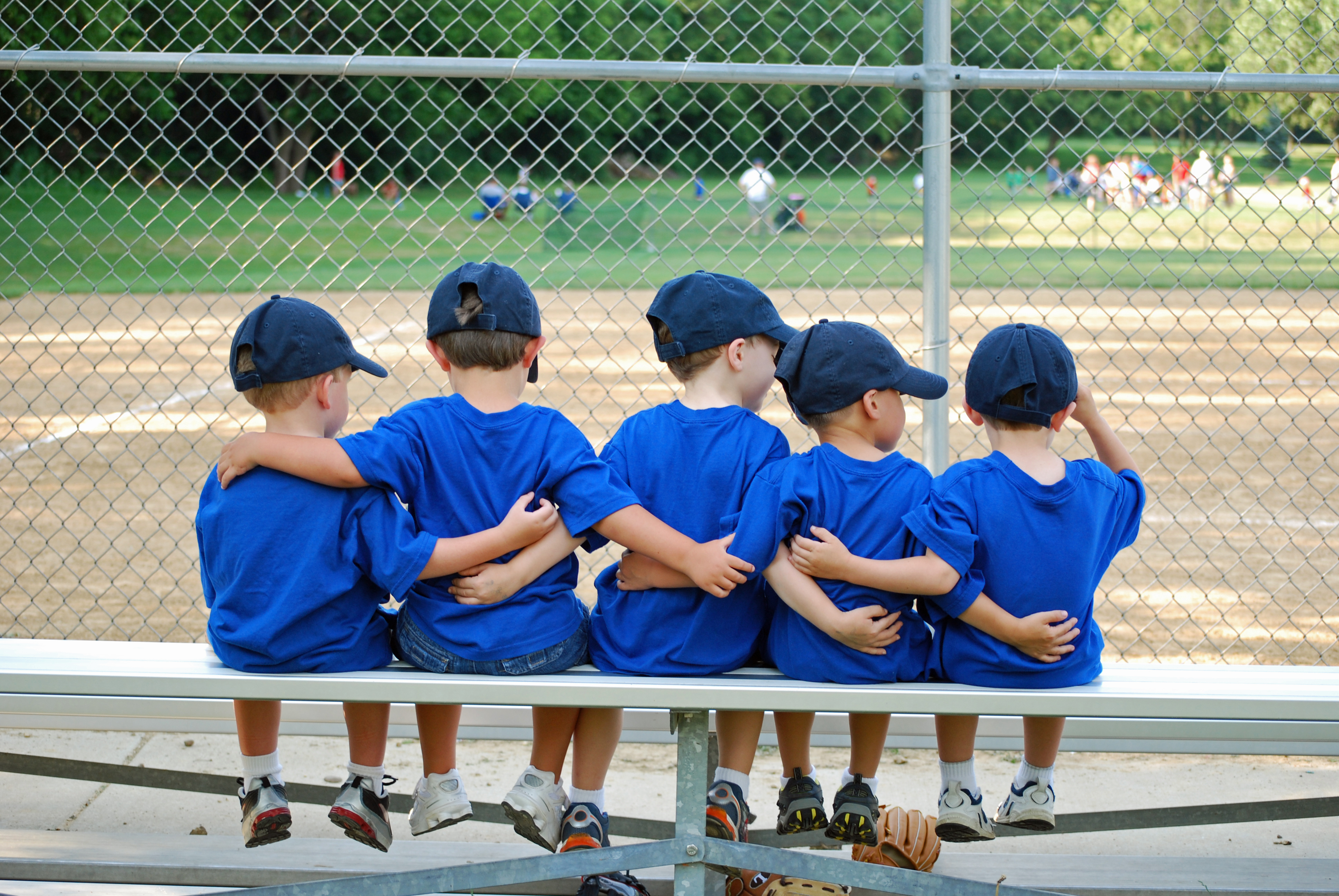 Vijf jongetjes met de armen om elkaar voor of na baseballwedstrijd