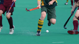 Drie hockeyspelers vechten om bal met stick