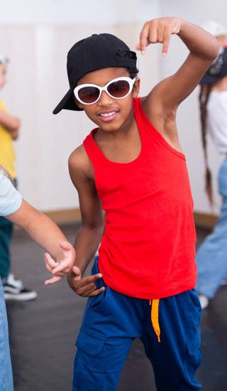 Meisje en jongen met pet en zonnebril tijdens groepsles in dansstudio
