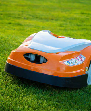 Automatic lawn robot mower moves on the grass slope, lawn. Close up side view
