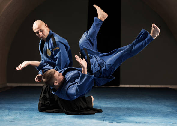 Twee mannen in blauwe kimono, ene valt met rug op de grond