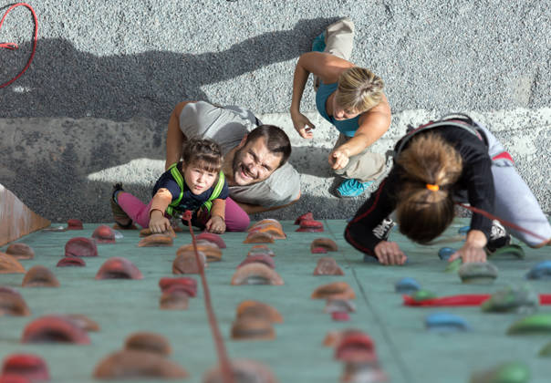 Little baby girl doing first steps on climbing wall while Happy Parents teaching her